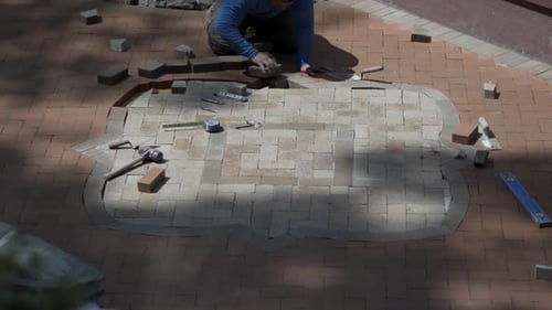 Bricklayer Installing Paving Brick on Hands and Knees