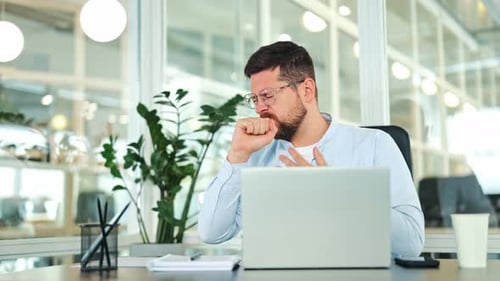 Unwell Businessman Coughing at Office Desk with Discomfort