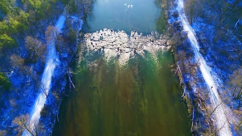Aerial Shot of a Serene River Winding Through Snowy Winter Woods