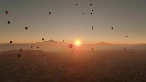 Drone view of hundreds of colorful hot air balloons soaring at sunrise in Cappadocia
