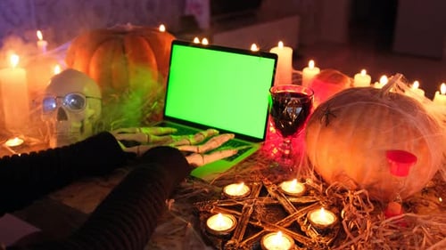 Vista lateral, manos esqueléticas escriben dramáticamente en el teclado del portátil con una pantalla verde