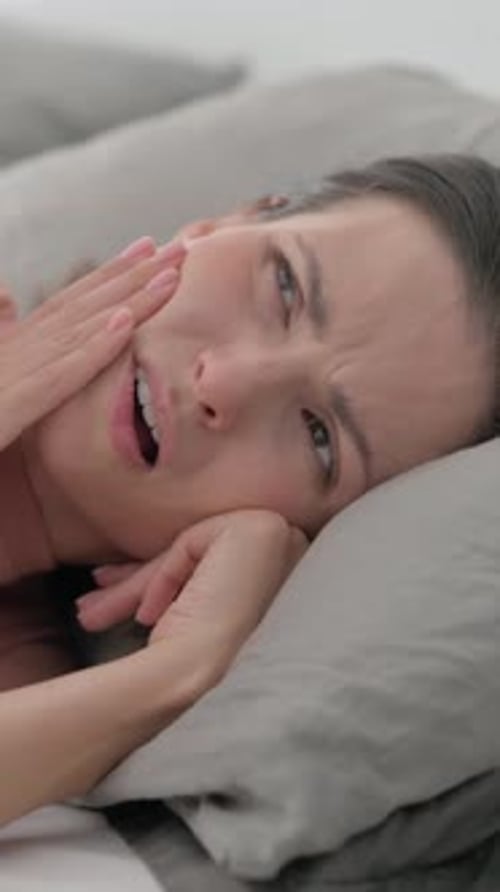 Woman Lying in Bed Experiencing Painful Toothache