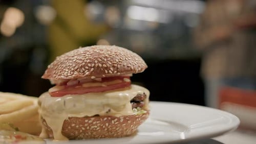 Nahaufnahme - Burger mit Pommes frites auf einem Drehtisch in einem Restaurant, ein funktionierendes Restaurant in Unschärfe