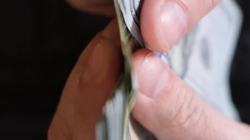 Nahaufnahme der Hand eines Geschäftsmannes, der 100-Dollar-Scheine in bar zählt (Vertikales Video)
