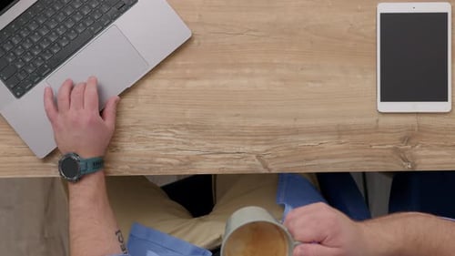 Close Up Top Down View of Working Unrecognizable Man at Laptop Drinking Coffee Guy in Blue Shirt is