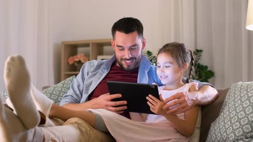 Father and Daughter Using Tablet on Sofa Together