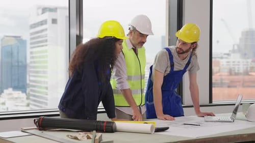 Engenheiros usando o plano de projeto, discutindo e trabalhando