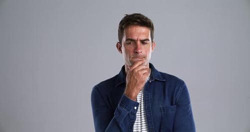 Gesicht, Lächeln und Idee mit einem jungen Mann im Studio isoliert auf grauem Hintergrund zum Entspannen beim Fühlen