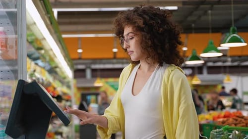 Woman Using Self Checkout Kiosk in Supermarket