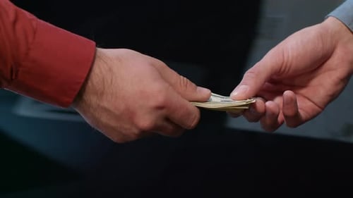 Two Men Handing Over Cash and Shaking Hands