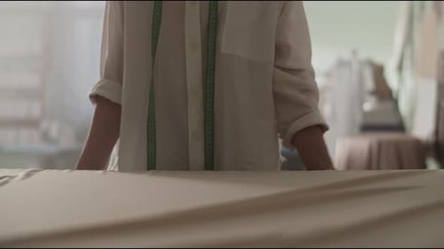 Female Tailor Placing Dress Material on Table in Studio