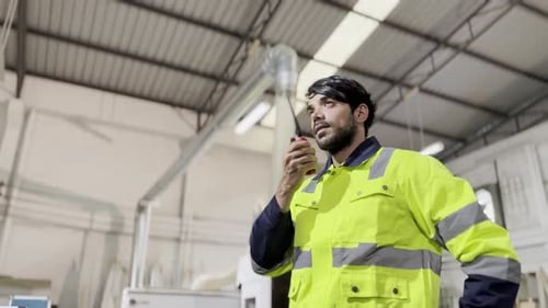Foreman Talking On Mobile walkie talky inside manufactory.