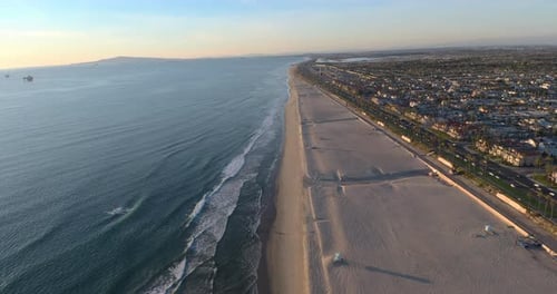 A 4K aerial drone view of a beautiful sunset with the ocean on one side and the cityscape on the oth