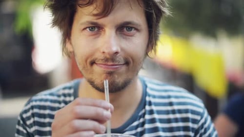 4k video footage of a young man enjoying some orange juice while out and about in the city