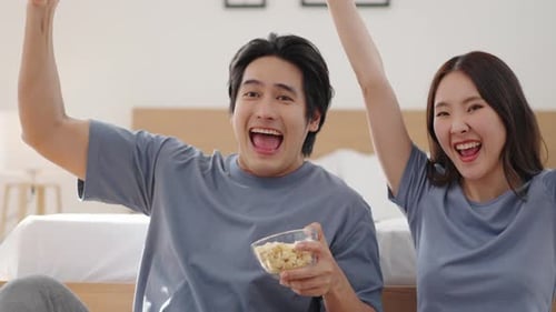 Couple Cheering and Watching Sports in Bedroom