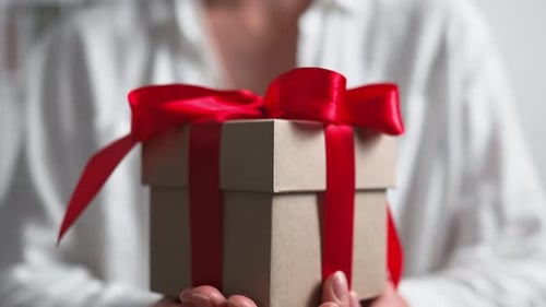Woman Holds Present with Red Bow Close Up