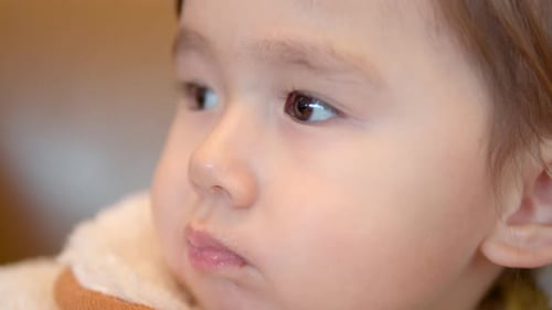 Closeup Portrait Of Cute 3-Year-Old Girl With Mouth Chewing Food Inside A Shopping Mall. - Closeup