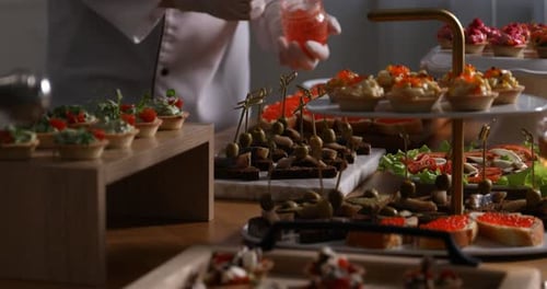 Chef making sandwiches with red caviar for buffet at table indoors, closeup