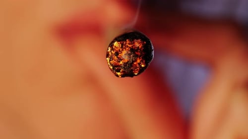 Frau zündet eine große konische CBD-Marihuana-Zigarette oder einen Drogenjoint mit einer Feuerzeugfigur an, Makro-Nahaufnahme