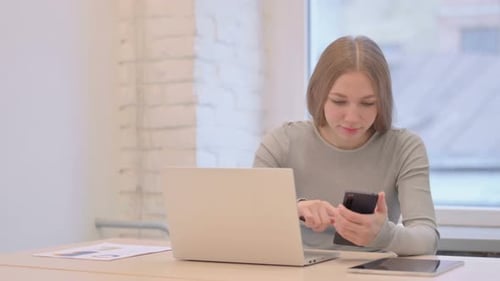 Woman Uses Laptop and Smartphone at Desk