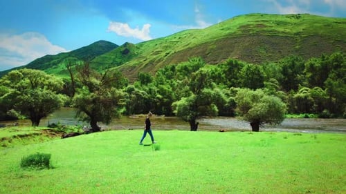 Young woman near mountain river against backdrop mountains. Beautiful landscape