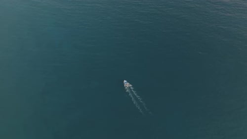 Aerial view of a motorboat sailing along the coast in Sicily, Italy.