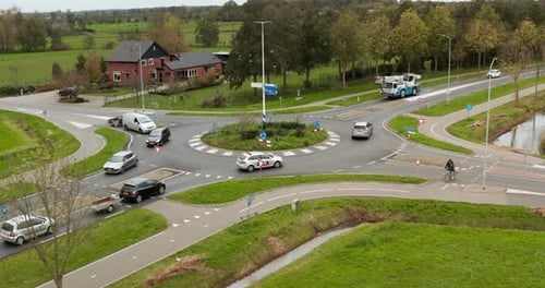 Drone shot of dutch roundabout with cars, bikes, trailors, vans, heavy transportation vehicles passi