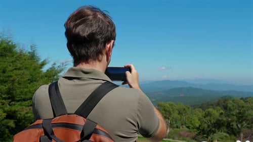 Man Hiking and Taking Photo of Scenic Landscape with Smartphone
