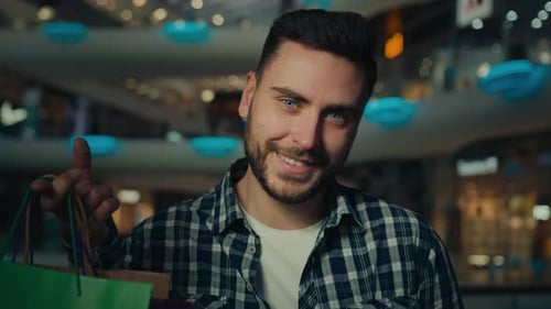 Man Smiling Holding Shopping Bags in Retail Mall
