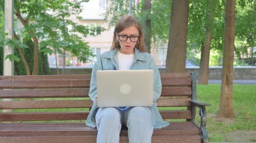 Perplexed Woman Using Laptop on Park Bench