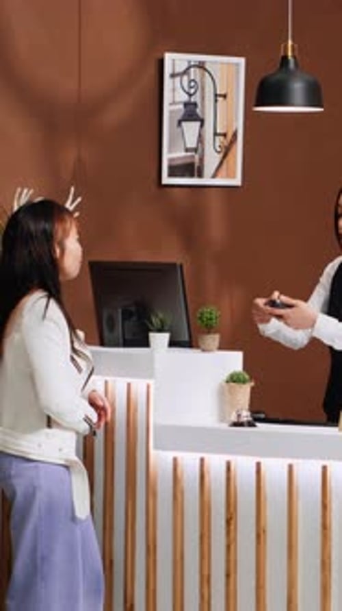 Vertical Video Asian Traveler Paying for Hotel Room During Check in Process
