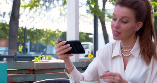 Woman Video Chatting on Phone at Outdoor Cafe