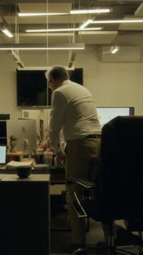 Vertical of Man Leaving Office Late at Night and Saying Goodbye to Colleagues