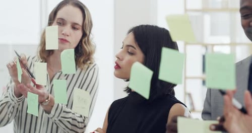 4k video footage of a group of businesspeople brainstorming with notes on a glass wall in an office