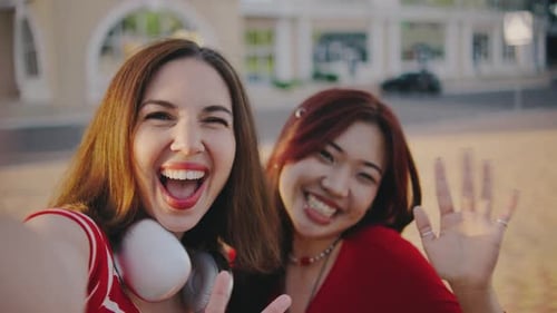 Two Girls Take a Selfie While Walking in the Park Girls in a Good Mood Take a Selfie on a Smartphone