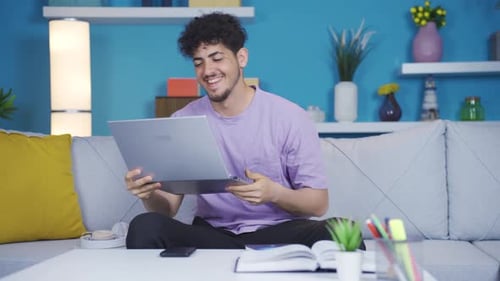 Happy Young Adult Works at Home on Laptop