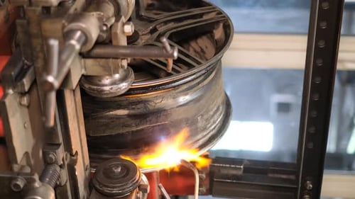 Welding Machine Repairs Automotive Wheel with Torch