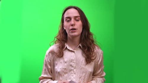 Modest woman presenter with long hair speaks, answers questions on chroma key