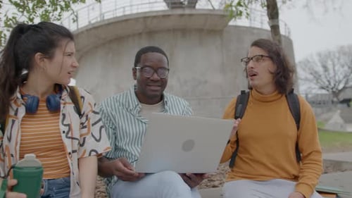Man Telling Story to College Friends Sitting Outdoors on Street Bench