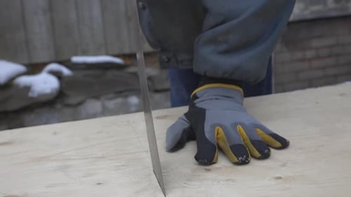 A Man Wearing Gloves Close To Finish Cutting The Planks Wood - Medium shot