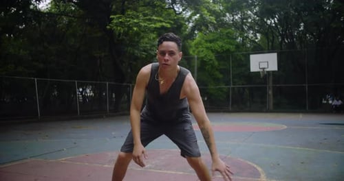 Homme hispanique dribble au basket sur le court du parc de la ville, en maintenant une concentration constante et athlétique