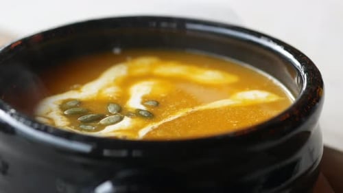 Köstliche Kürbissuppe in Schüssel auf Holztisch
