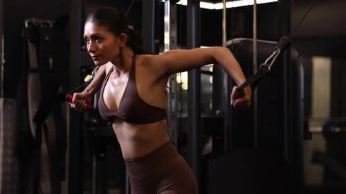 Strong Woman Doing Standing Cable Crossover Press At Gym