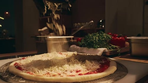 Hand of Chef Sprinkling Grated Cheese on Pizza Base in Restaurant