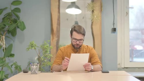 Man Reviews Documents at Desk in Office