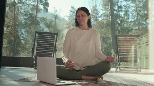 Woman Practicing Online Yoga in Front of Laptop at Home
