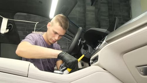 Young Man Detailing Car Interior with Brush