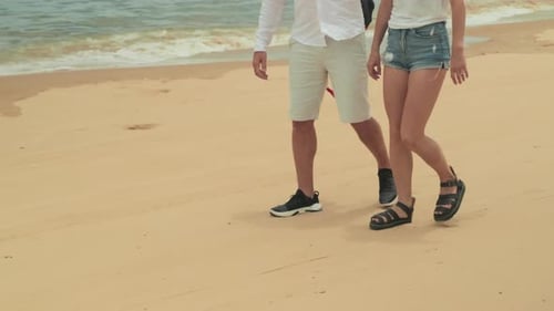 Young Carefree Couple Walking Along Sandy Beach At Tropical Resort