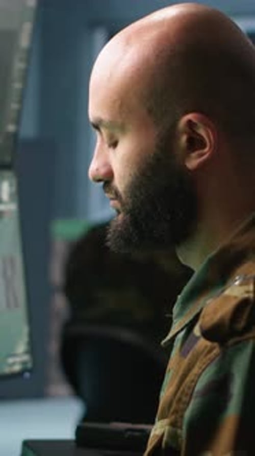Man in Camouflage at Computer in Dark Room