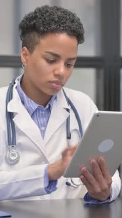Young Woman Doctor Uses Tablet at Desk